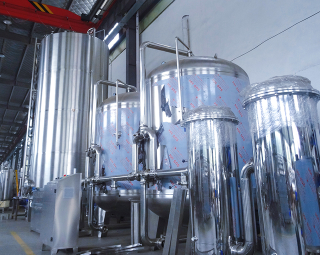 Industrial equipment includes large shiny metal tanks and pipes